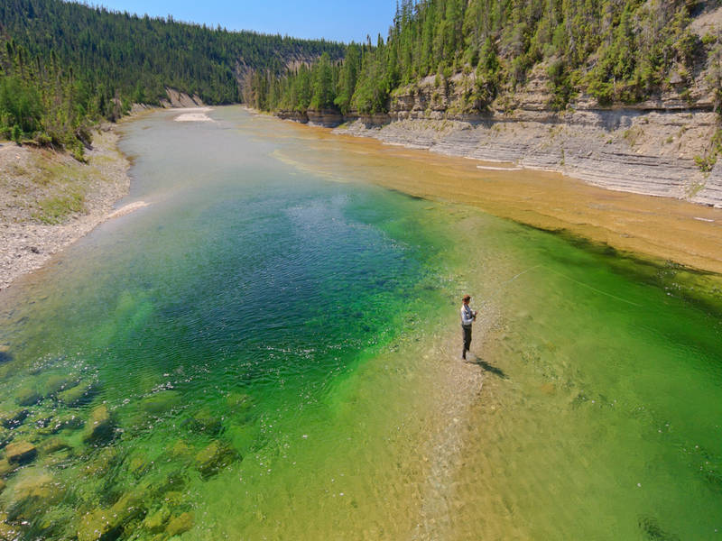 Un homme peche dans une rivière.