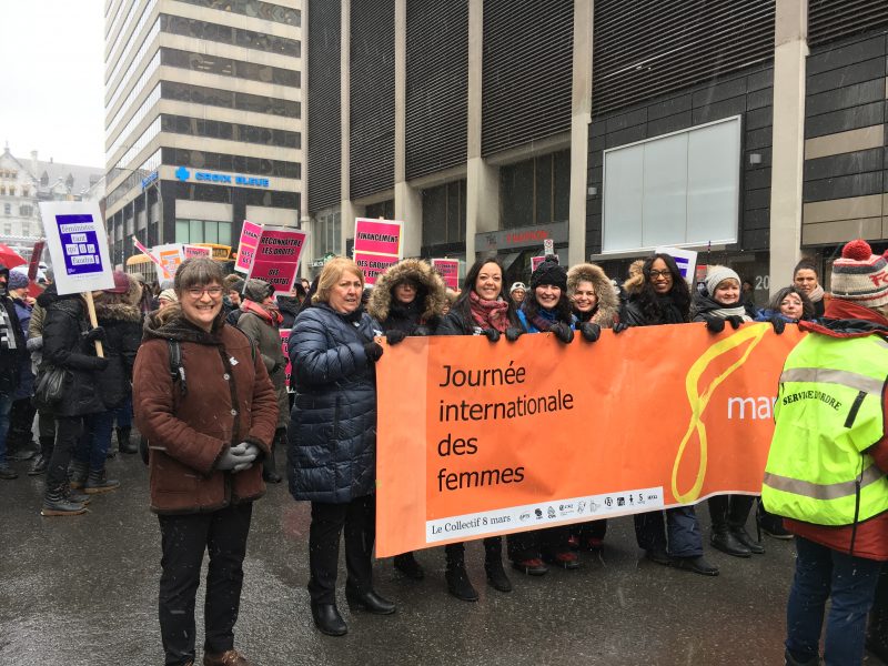 Femmes dans une manifestation du 8 mars pour les droits des femmes tenant une bannière.