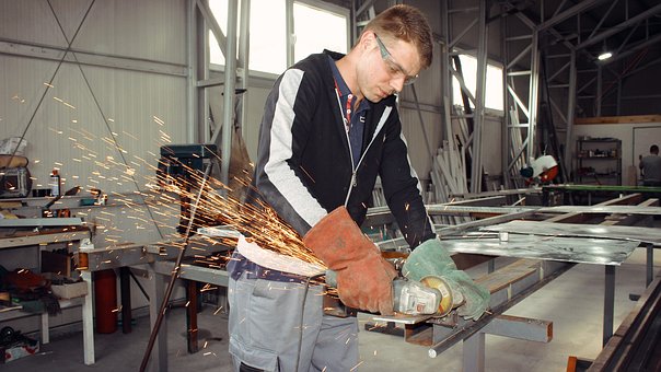 Homme portant un gant en train de travailler le métal.