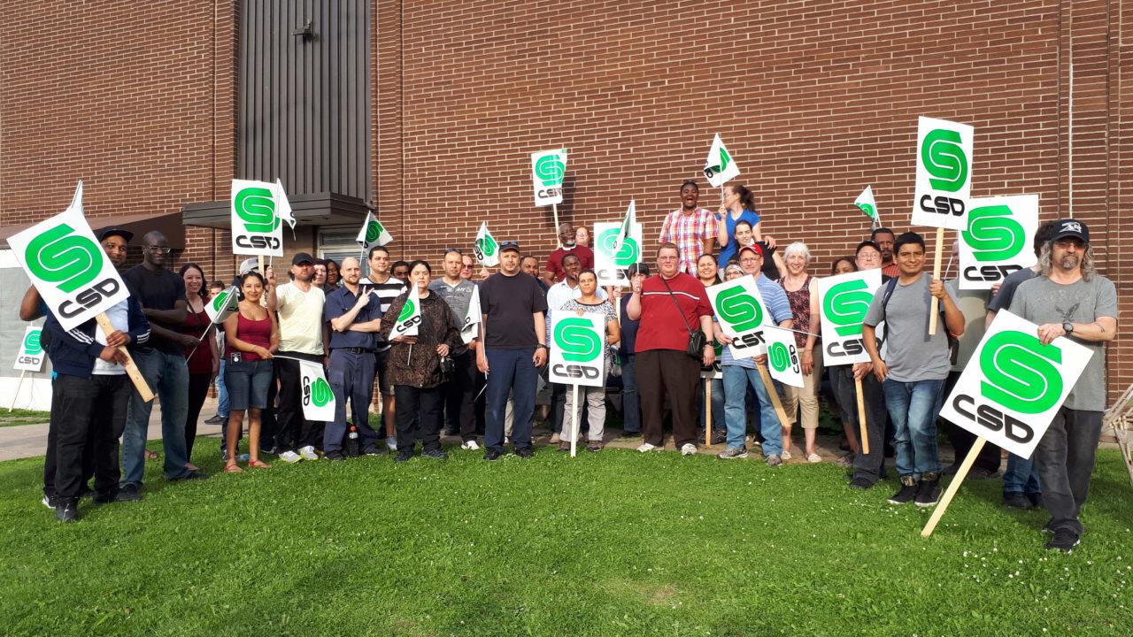 Groupe de militants tenant des pancartes de la CSD devant l'usine Olymel