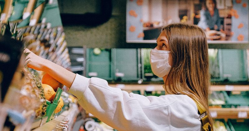 femme travaillant dans une épicerie avec un masque