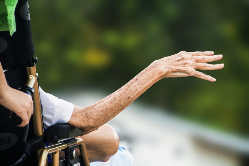 Bras d'une personne âgée sur un fauteuil roulant