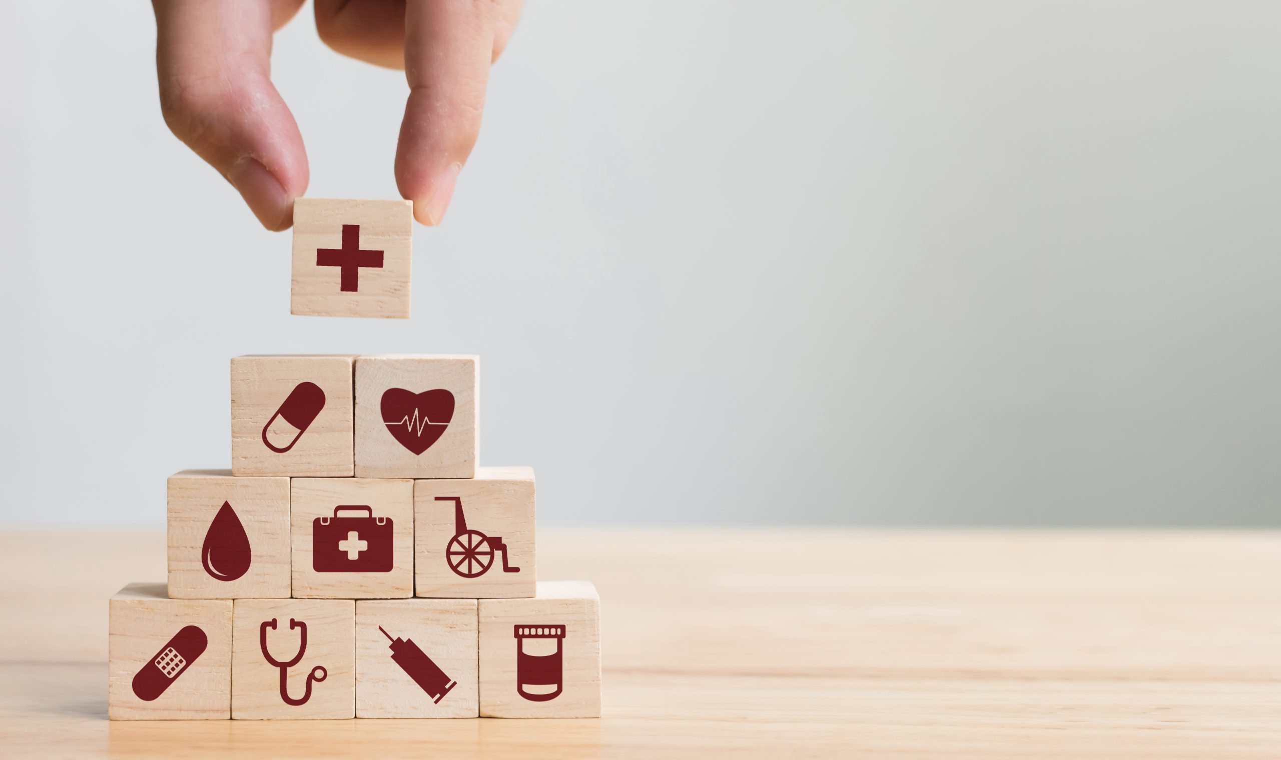 Blocs de bois empilés en forme de pyramide avec des dessins rouge représentants différents éléments de la santé.